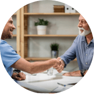 Happy doctor greeting and handshaking with senior patient at his office Focus is on senior man